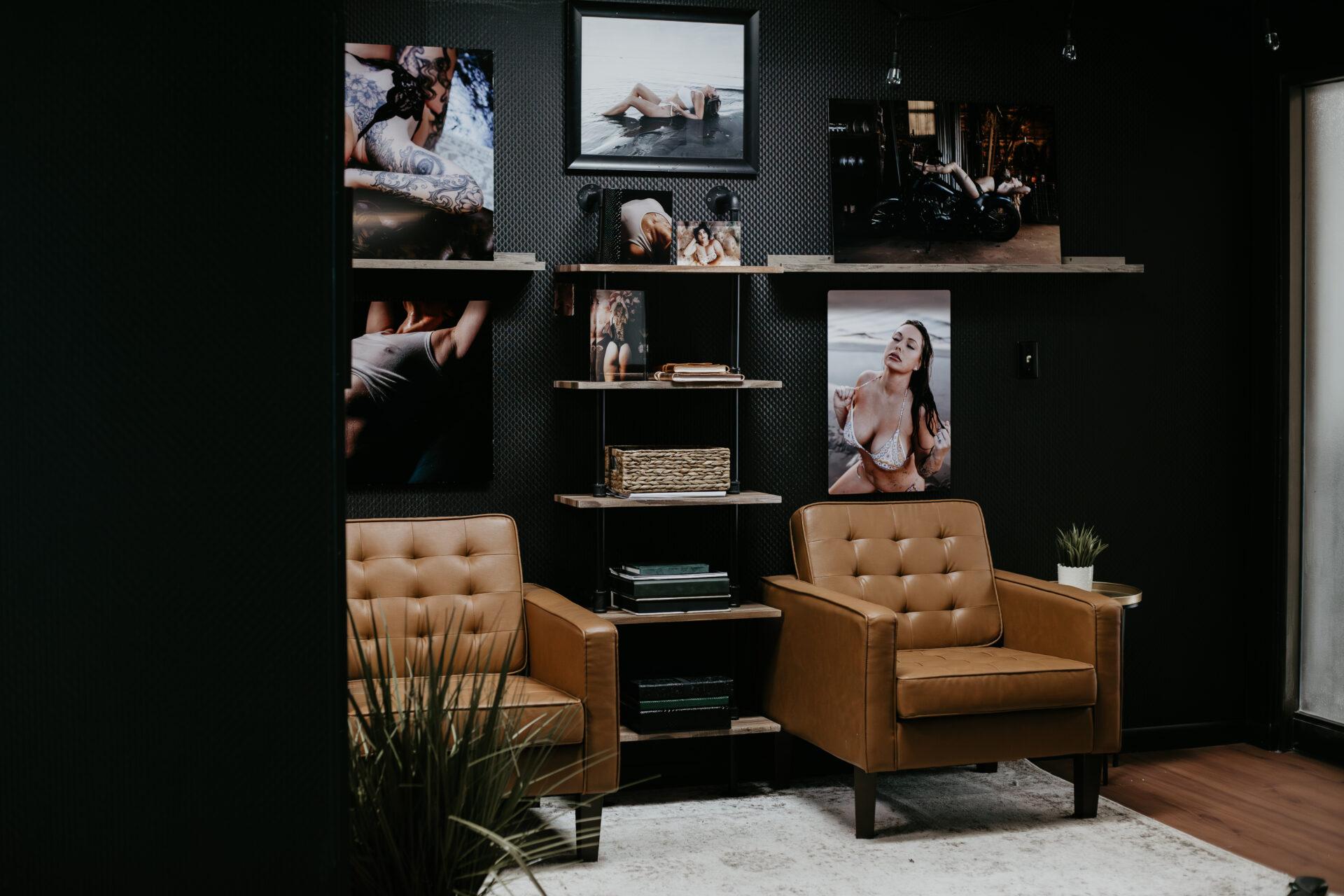 Modern boudoir photography studio lounge with leather chairs, wall art, and intimate printed portraits in Bay City, Michigan