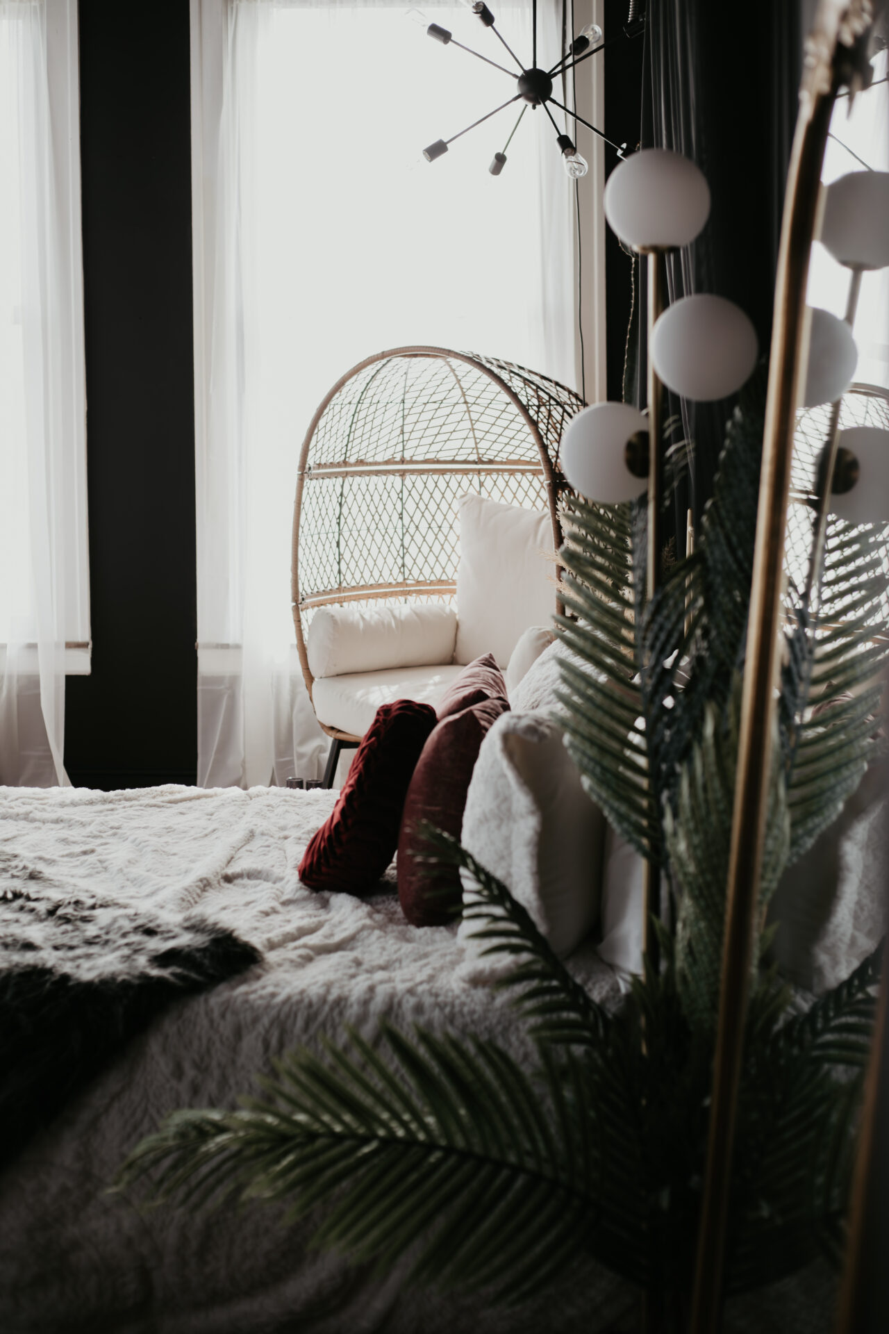 Cozy boho boudoir studio bed with textured bedding, velvet pillows, and rattan egg chair in Bay City, Michigan