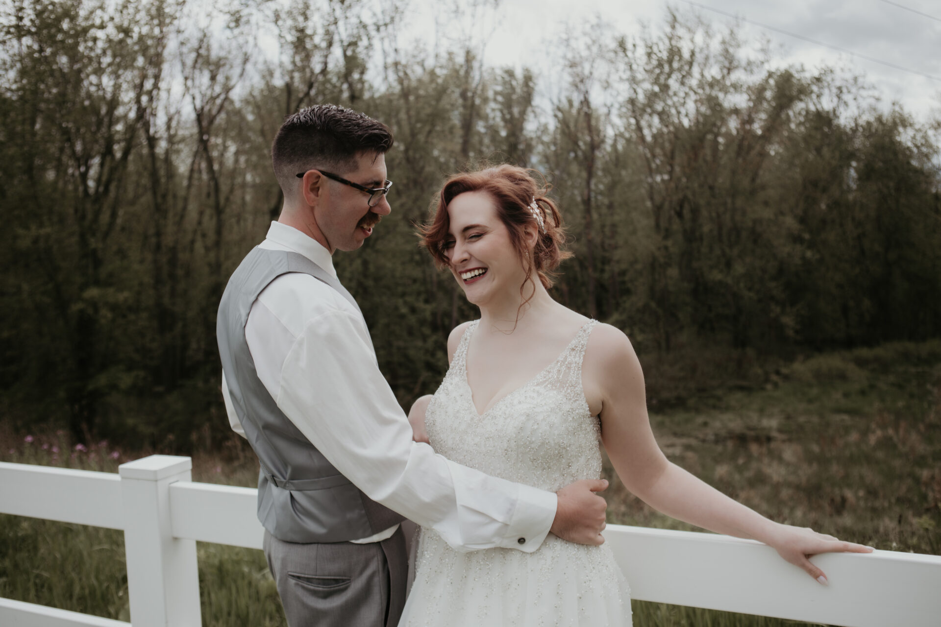 Bride and groom laughing together during a candid outdoor wedding moment in Michigan, captured by Arielle Roth Photography.