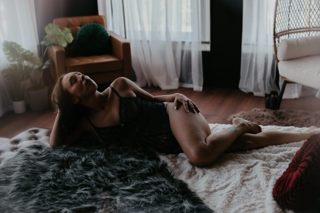 Mature boudoir client over 40 posing in black lingerie on a fur rug in Arielle Roth Boudoir’s Bay City, Michigan studio.