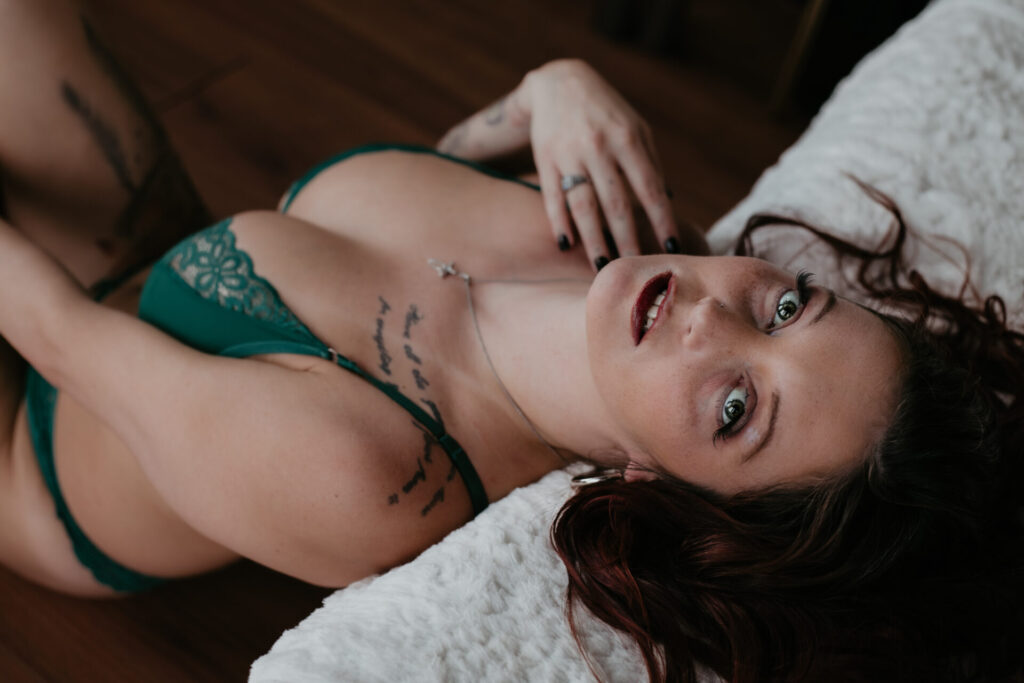 Bay City Michigan boudoir photographer – woman in green lingerie laying back on bed