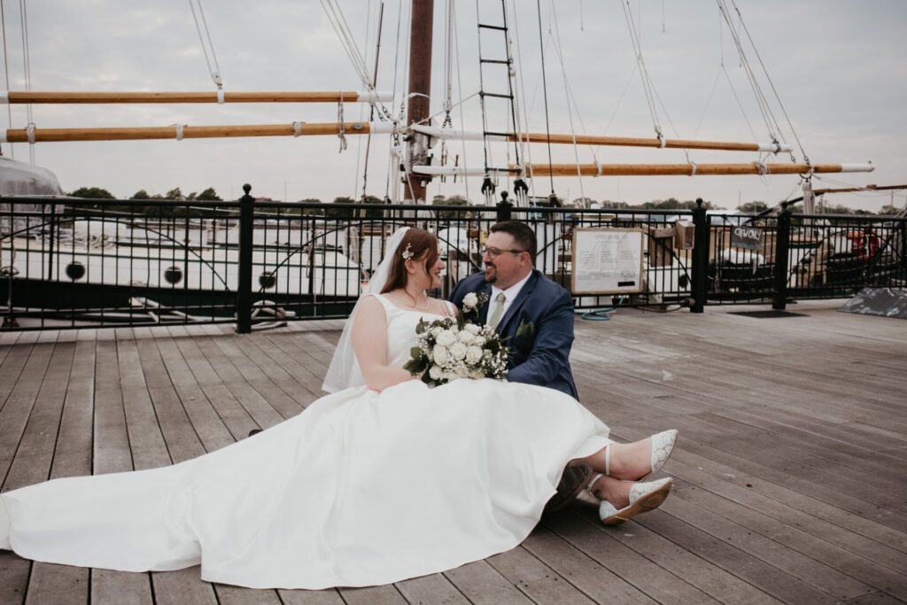 Bride and groom sitting together on the dock at DoubleTree by Hilton Bay City Riverfront in Downtown Bay City, Michigan