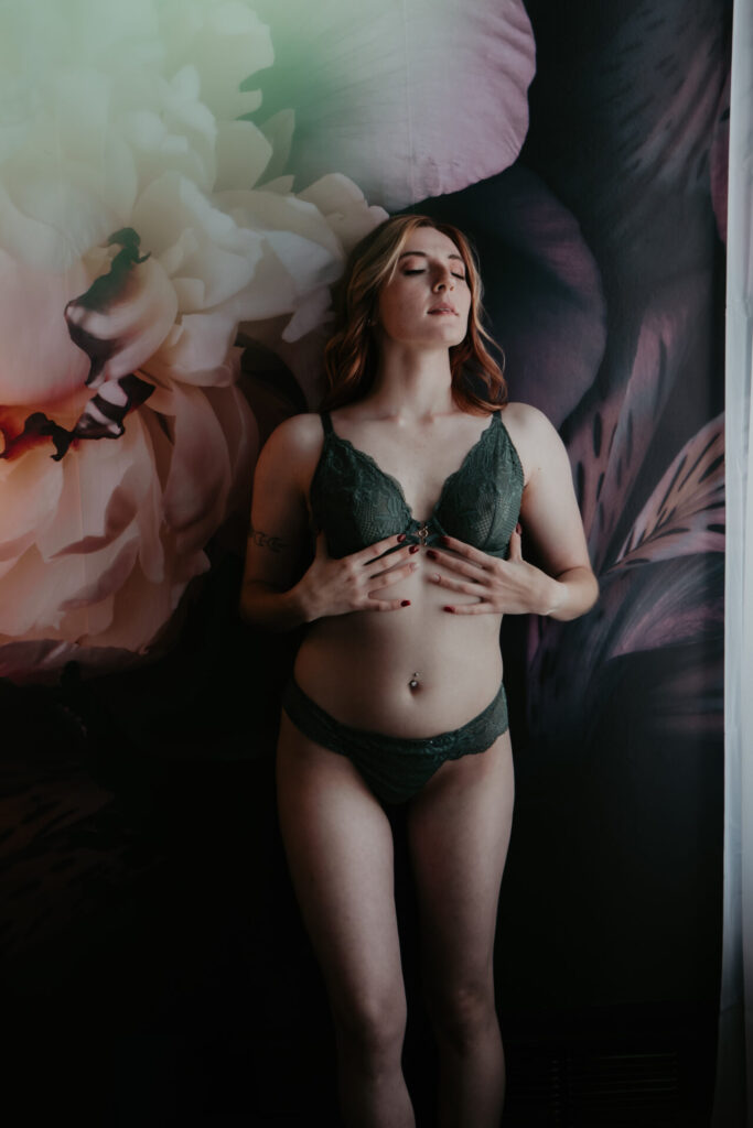 Boudoir photography in Bay City Michigan with woman in green lace lingerie against floral wall
