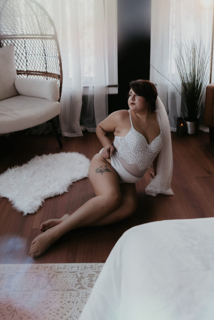 Bridal boudoir session Bay City Michigan bride in pearl bodysuit and veil on studio floor