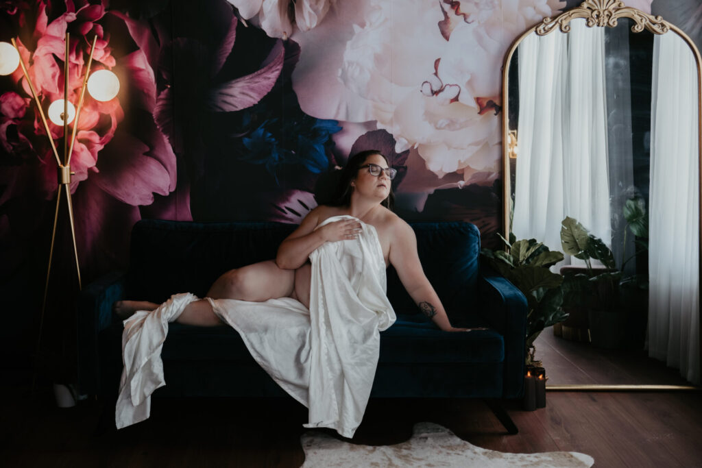 Over 40 boudoir photography in Bay City Michigan studio with floral wall and silk sheet.
