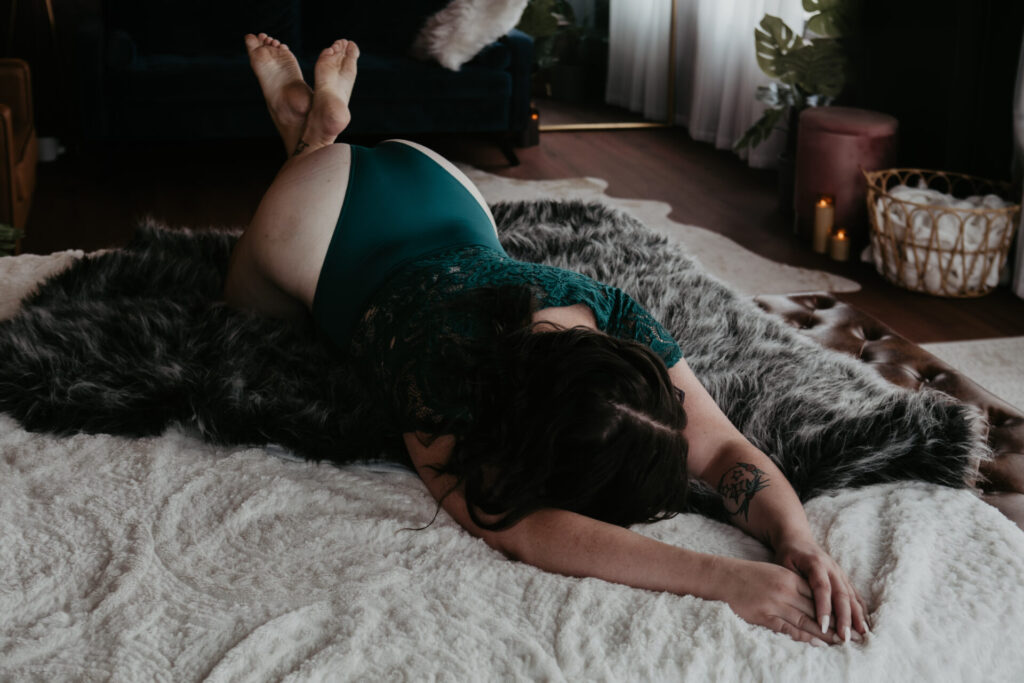 Mature boudoir photography in Michigan featuring a Saginaw client in teal lace lingerie on a fur blanket.
