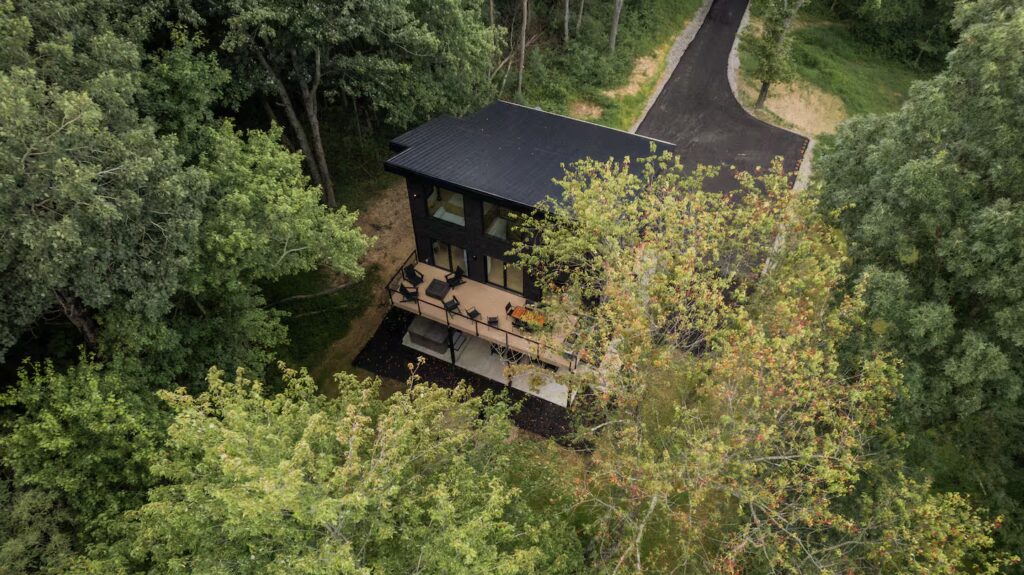 Aerial view of a modern cabin with deck surrounded by forest in Hocking Hills Ohio where the Wild Confidence Retreat hosted by Michigan boudoir photographer Arielle Roth takes place.