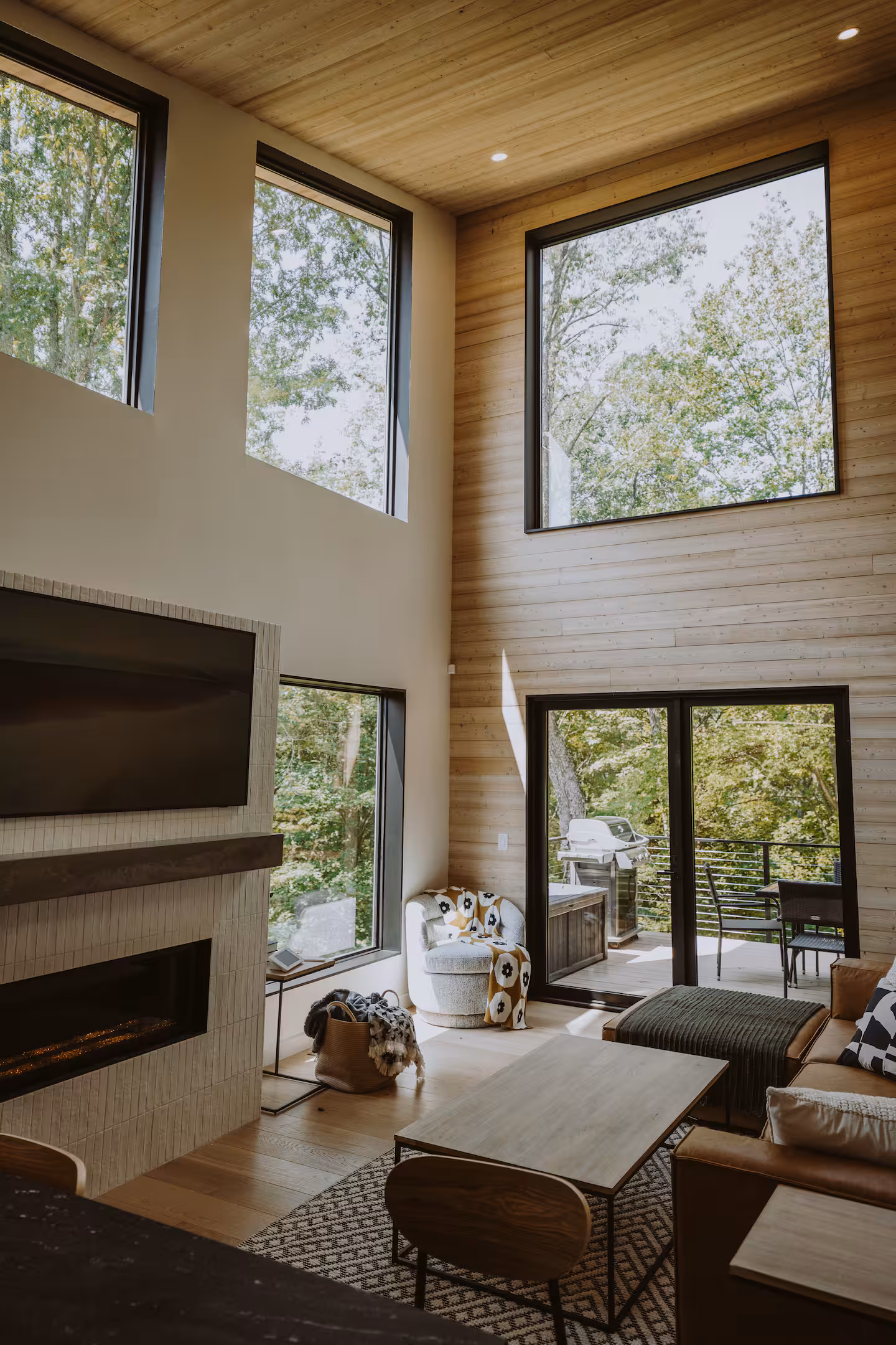 Bright modern Airbnb living room in Hocking Hills Ohio with tall windows, leather sofa, and natural wood interior used for the Wild Confidence Retreat hosted by Michigan boudoir photographer Arielle Roth.